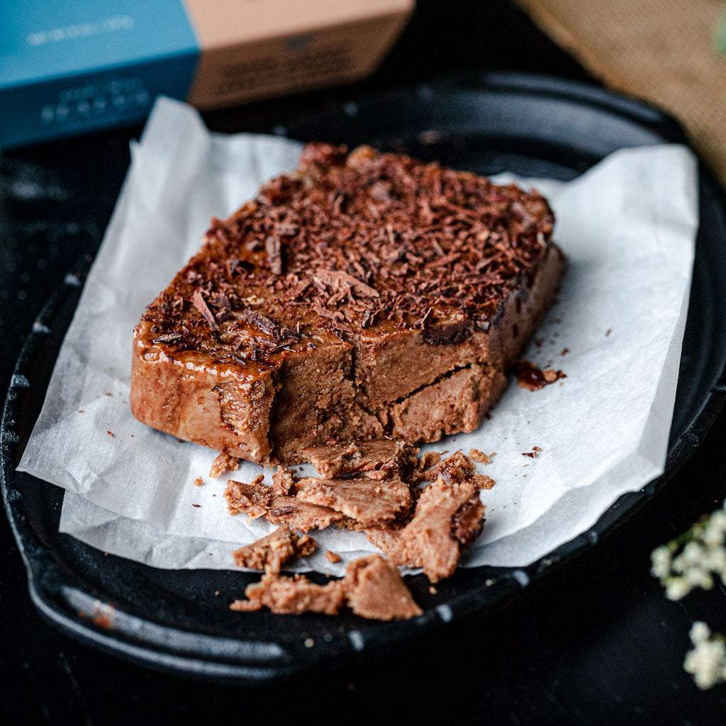 A plate of sea salt dark chocolate halva that is crumbling at one corner.