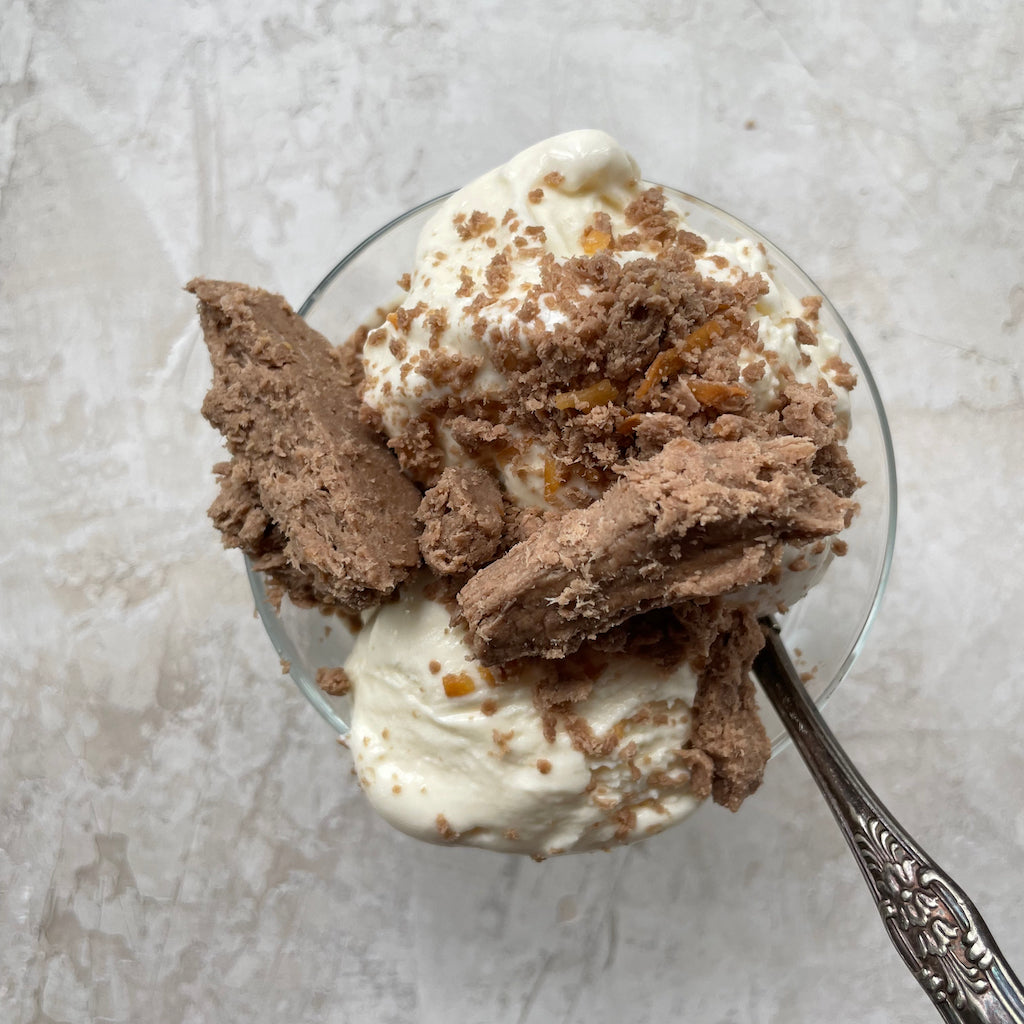 A bowl of ice cream covered in halva with a spoon on the side.