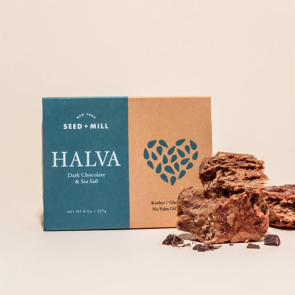 A box of sea salt dark chocolate halva with crumbled halva on the side.