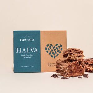 A box of sea salt dark chocolate halva with crumbled halva on the side.