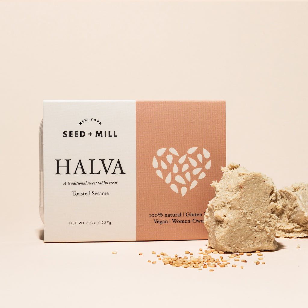 A box of toasted sesame halva with crumbled halva on the side.