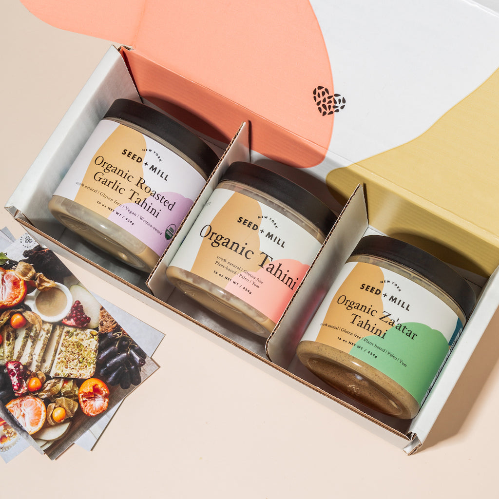 An image of three tahini jars in a shipper box with a recipe card on the side.